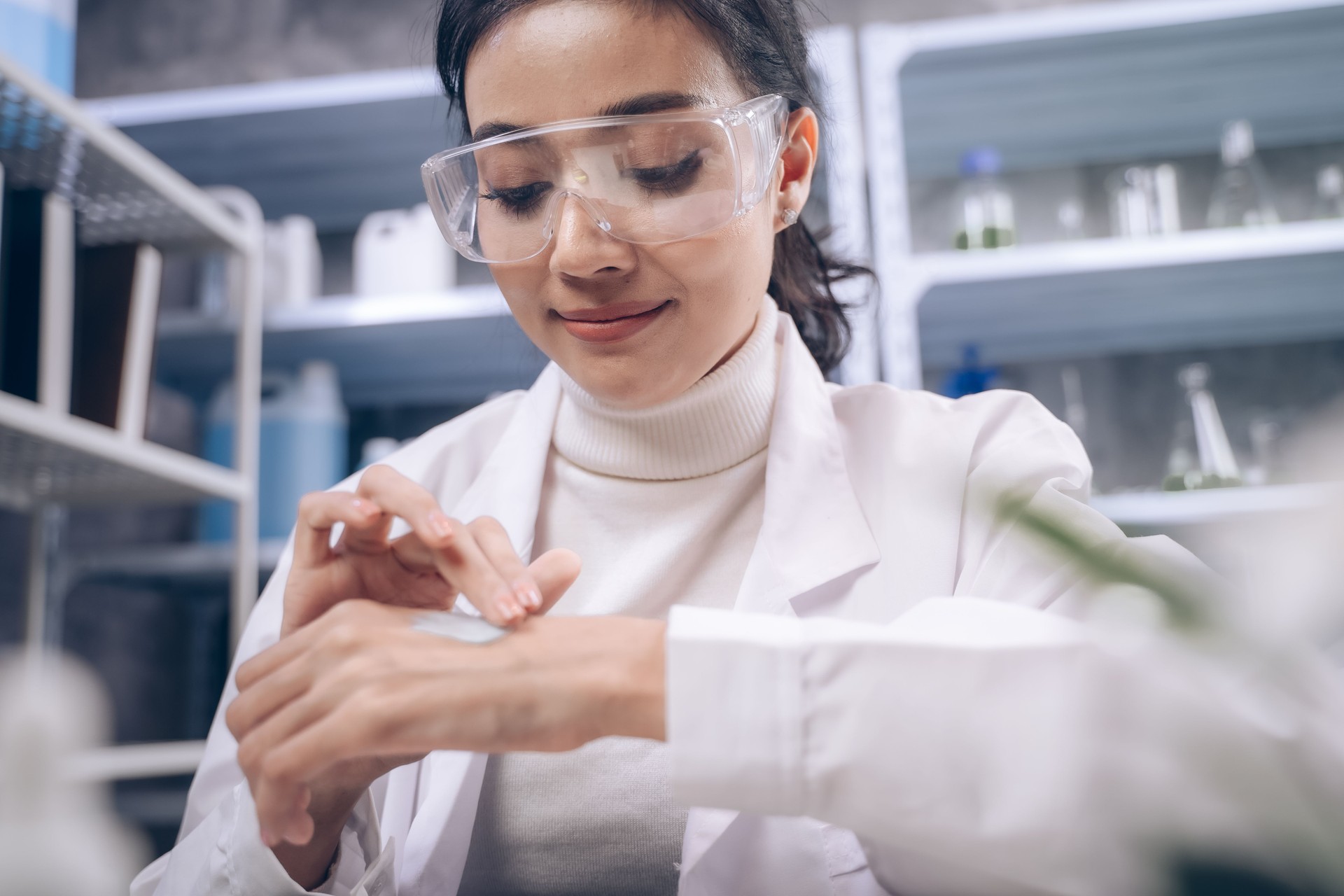 A young researcher is pouring cream on his hands in a laboratory. woman testing cosmetics or medicine for beautiful skin care